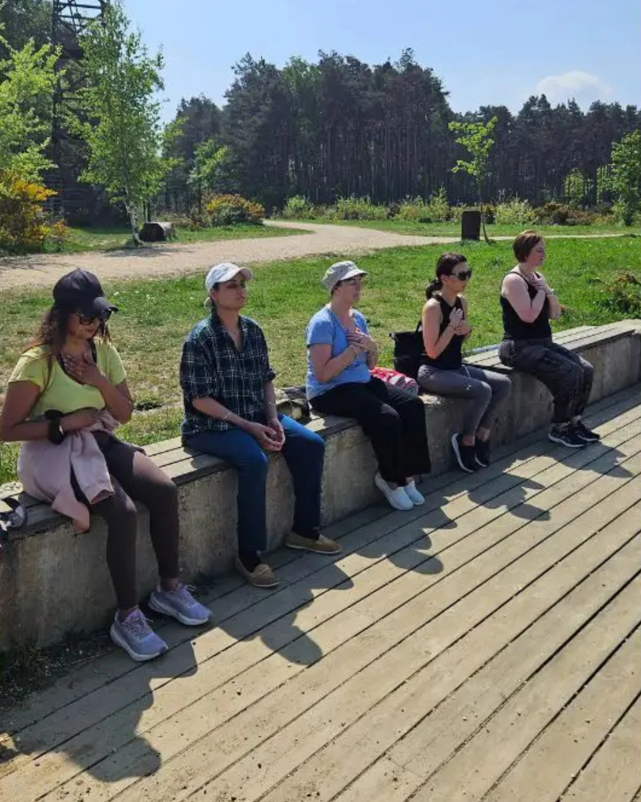 Small group of participants seated together on a wooden deck during a guided mindfulness and sharing circle at the Forest Retreat in Berkshire, UK.