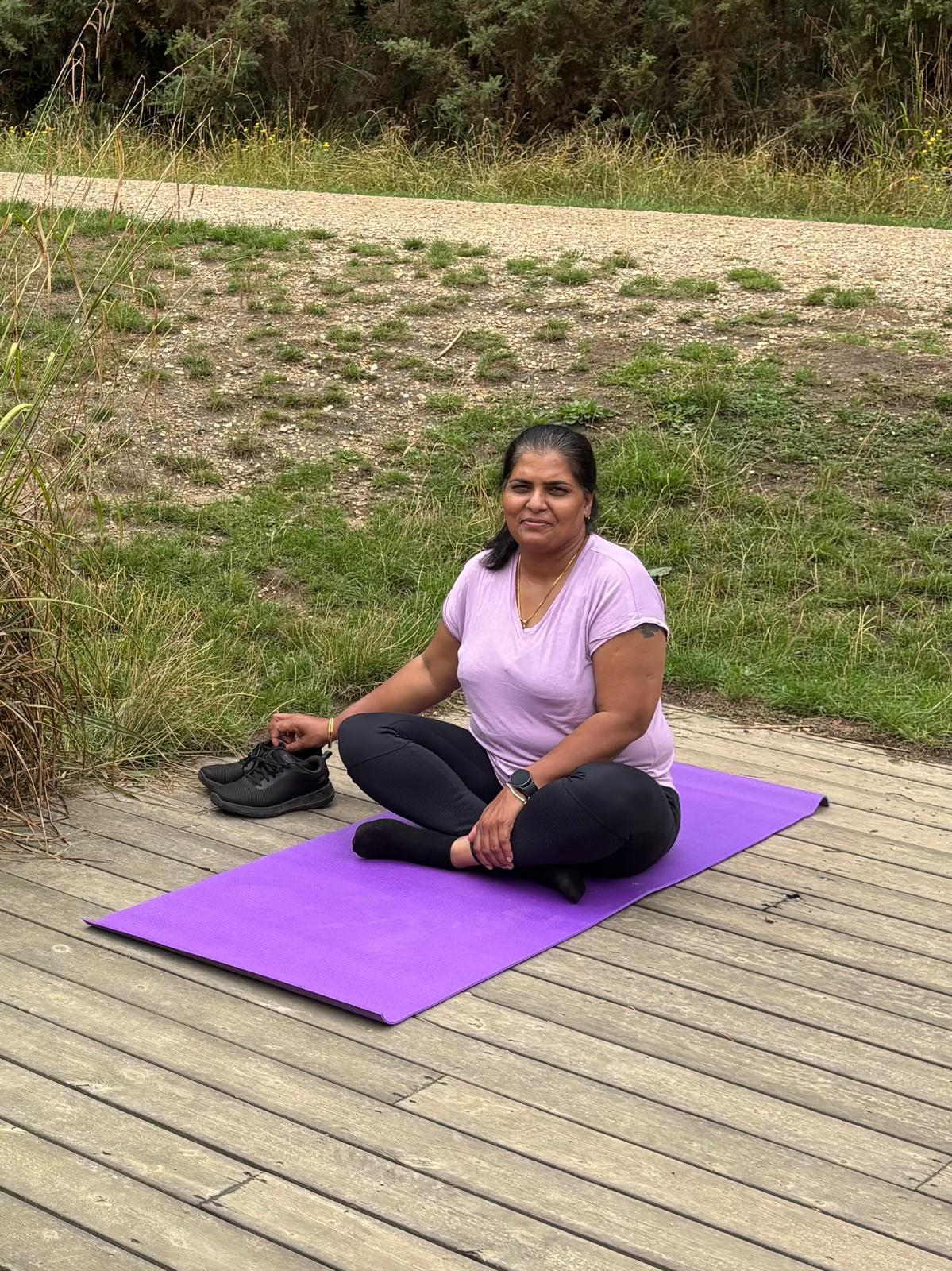 Female participant sitting cross-legged on a purple mat meditating during the Forest Retreat in Berkshire, connecting deeply with nature.
