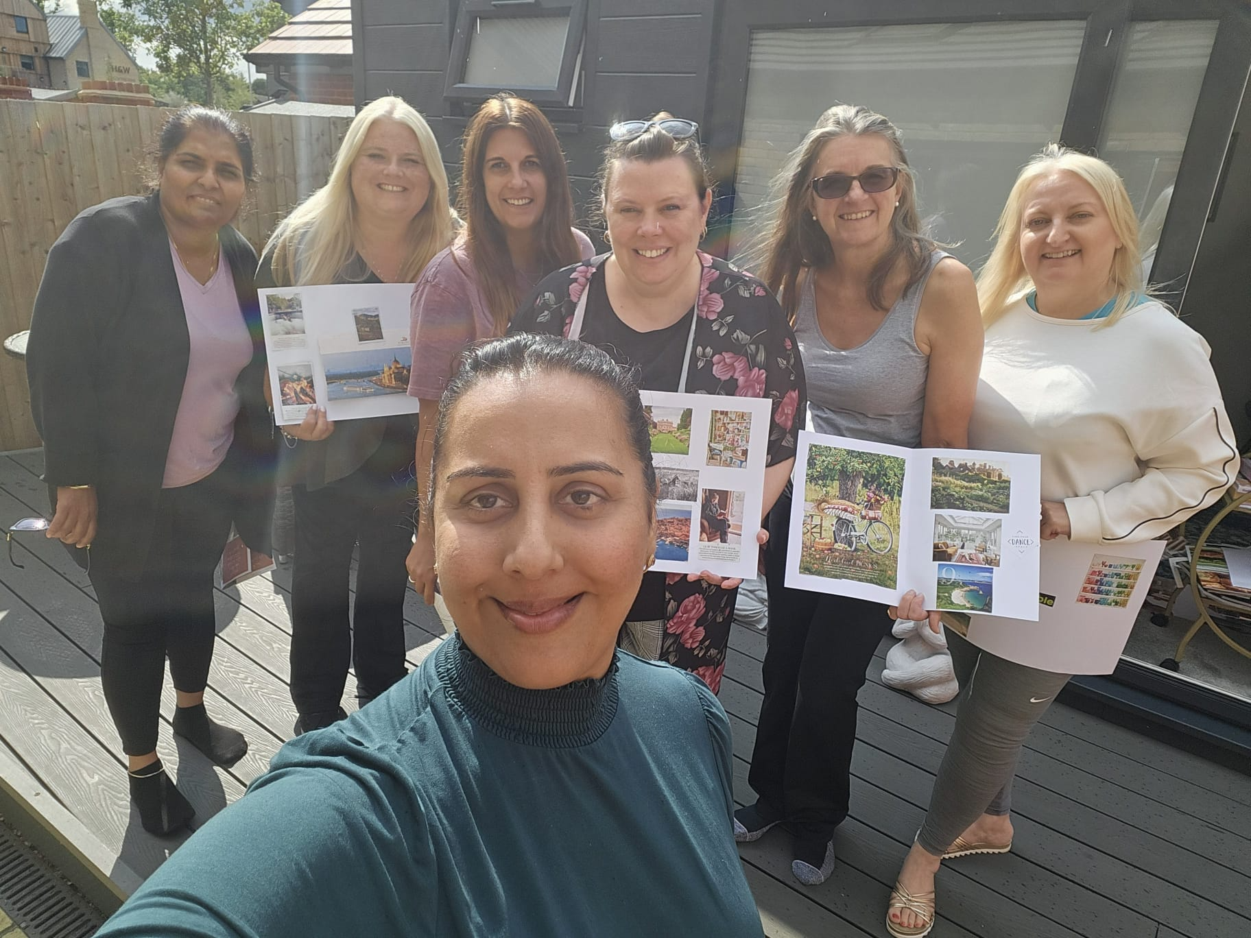 Group of participants smiling and holding up vision boards created during the Berkshire Forest Retreat by Nikita Thakrar, showing personal goals and intentions.