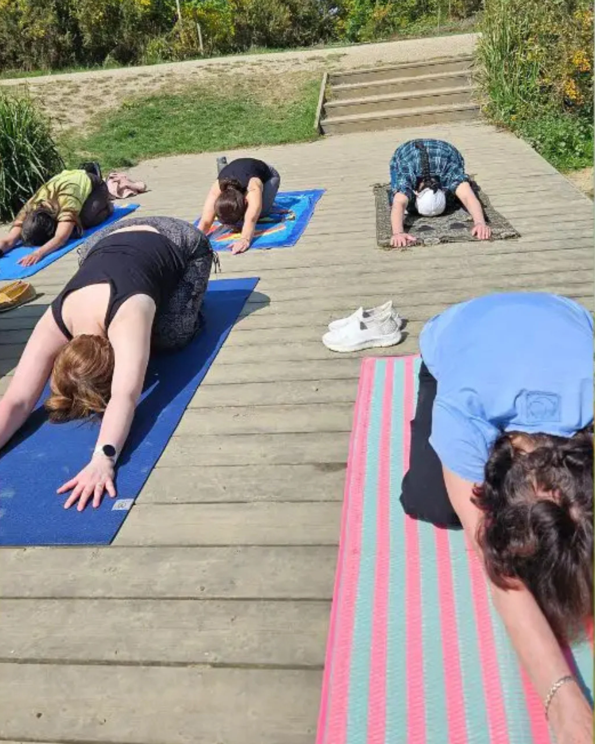 Participants practicing gentle yoga and breathwork on mats outdoors during the Forest Retreat in Berkshire, UK, in a calm forest environment.