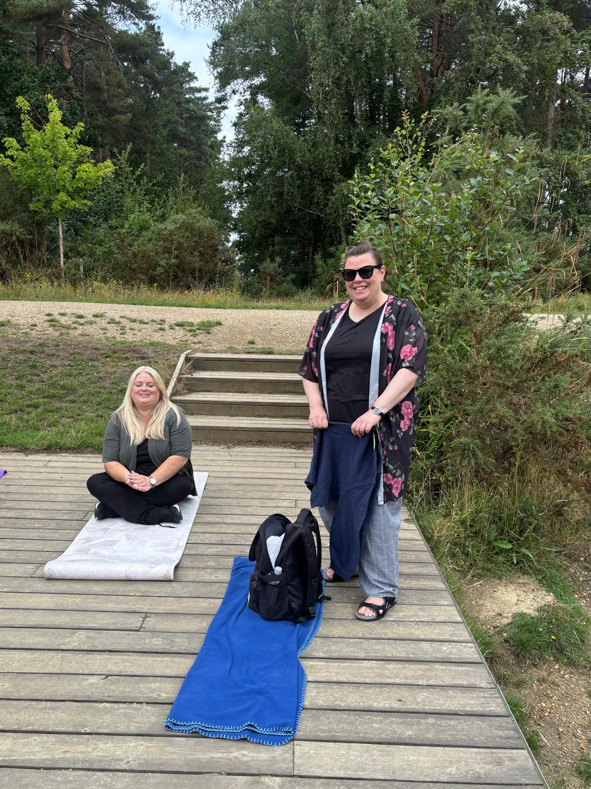Participants practicing seated yoga poses on mats on a wooden deck surrounded by forest during the Berkshire Forest Retreat.