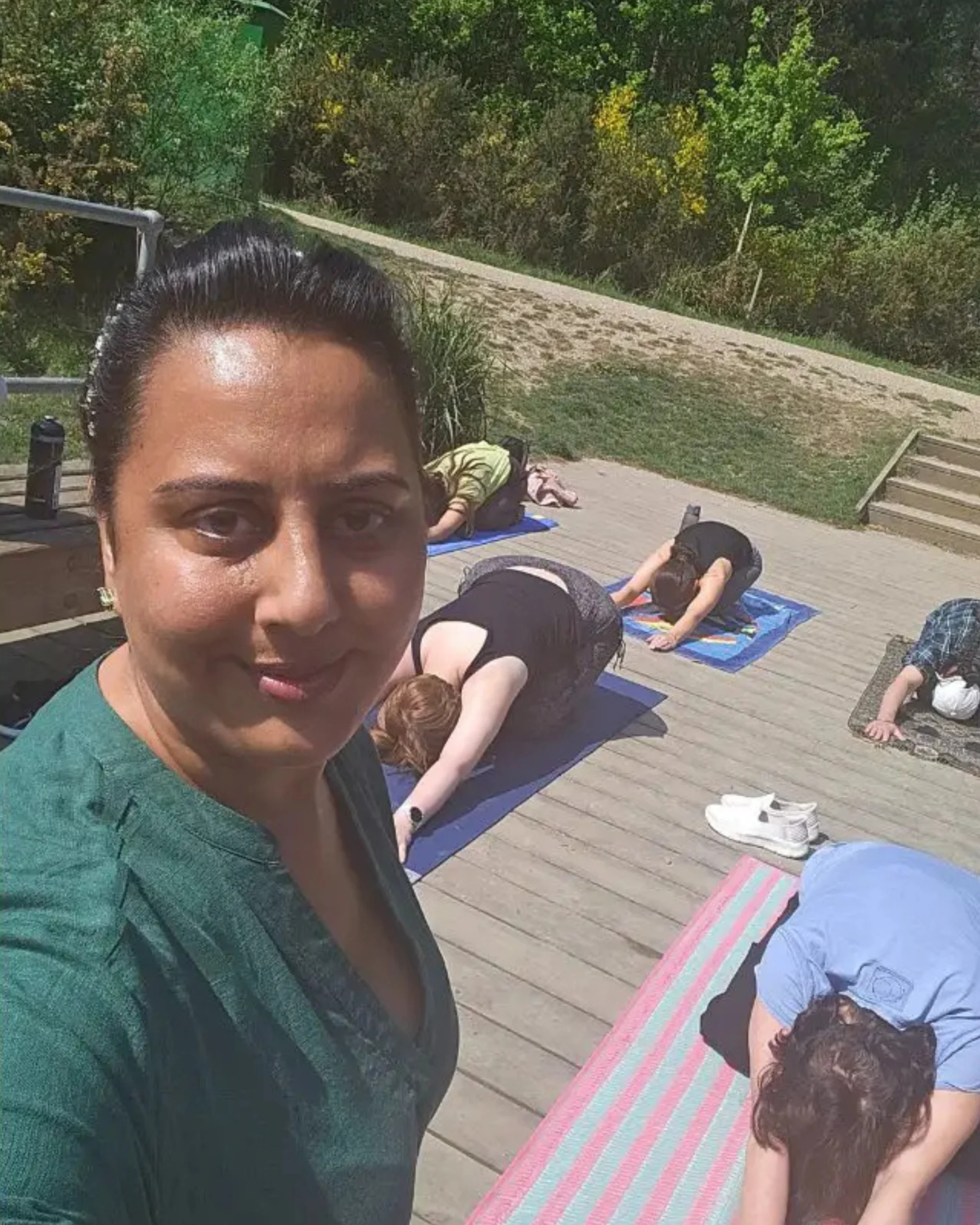 Retreat facilitator Nikita taking a selfie with participants practicing yoga on mats during the Forest Retreat in Berkshire, UK, in a peaceful outdoor setting.