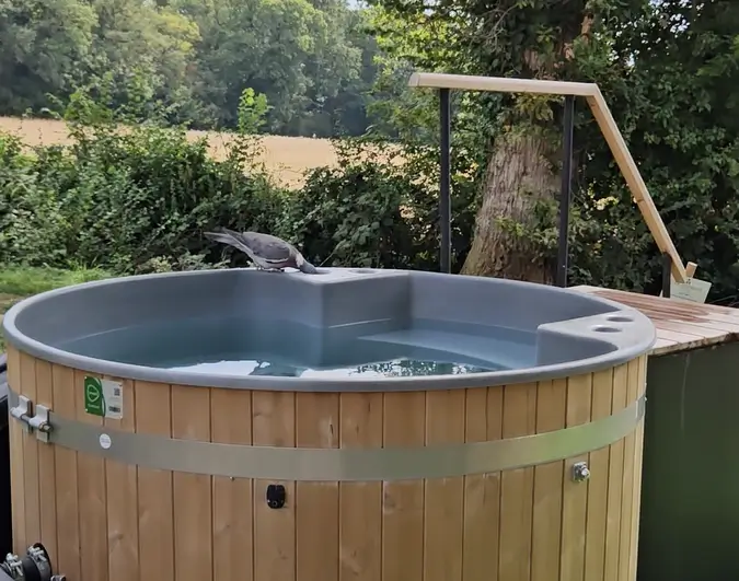 Outdoor wooden hot tub set in peaceful countryside surroundings at Elcot Park wellness retreat in Berkshire, UK
