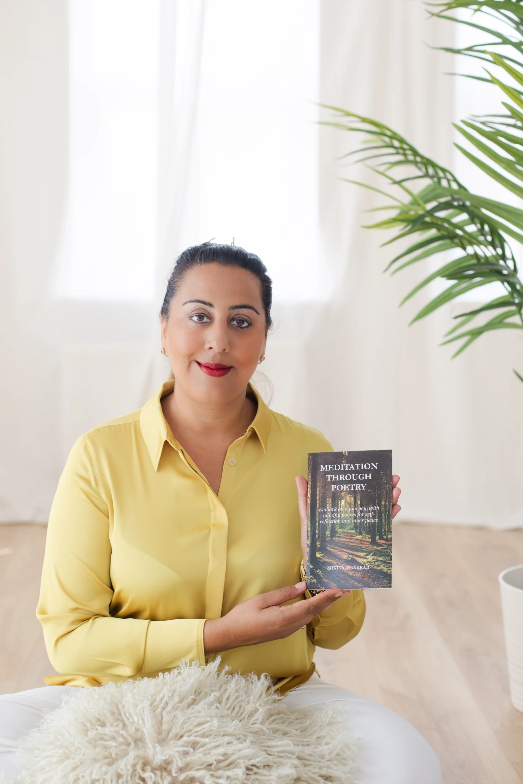 Nikita Thakrar holding her award-winning book Meditation Through Poetry, a mindfulness and healing poetry collection.