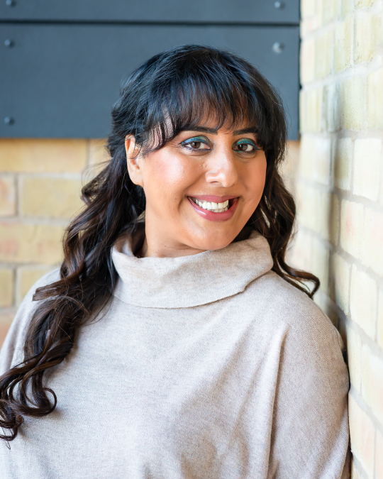 Portrait of Nikita Thakrar speaker for schools Berkshire UK, award-winning educator and youth mentor, smiling warmly in a calm indoor setting.