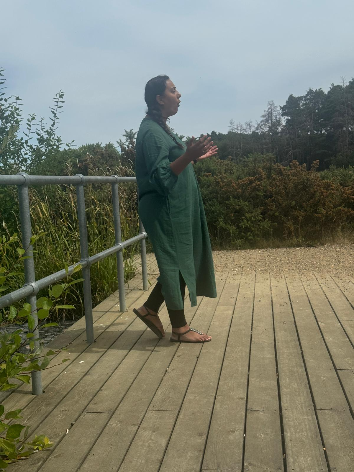 Nikita guiding a participant through a meditation session on a wooden deck surrounded by trees at the Berkshire Forest Retreat.